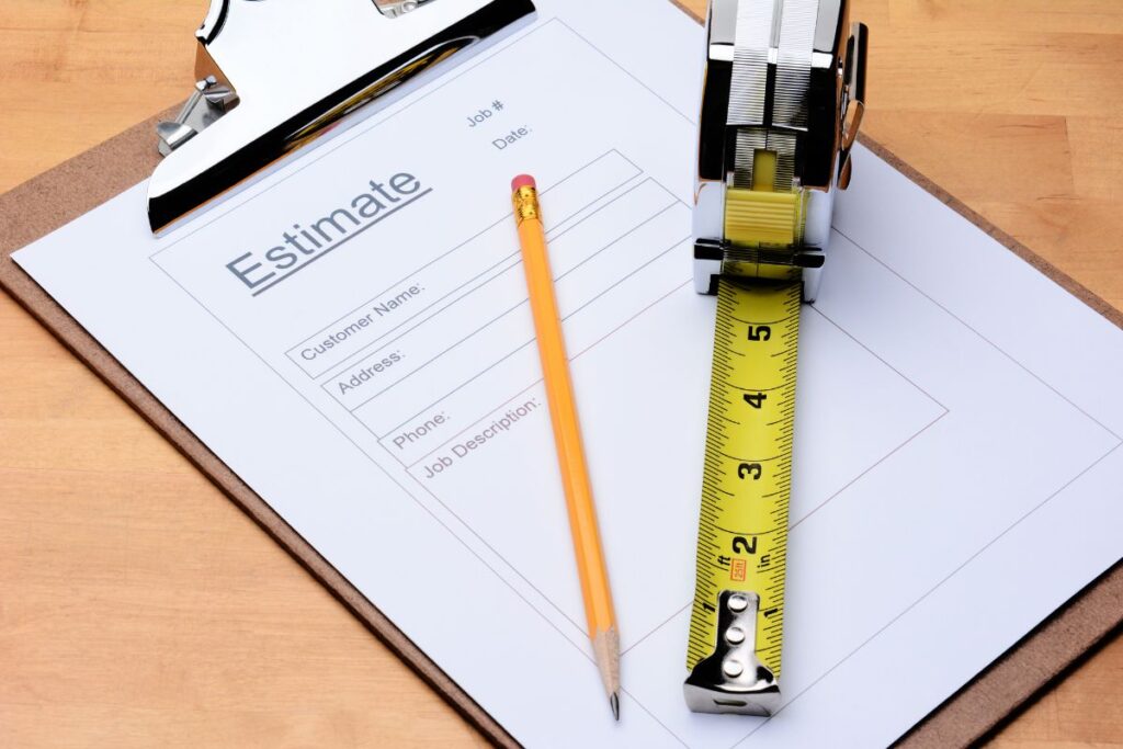 Image of a clipboard with a paper on top that says "estimate". This is an example of a cost estimate that a contractor might provide to a customer. 